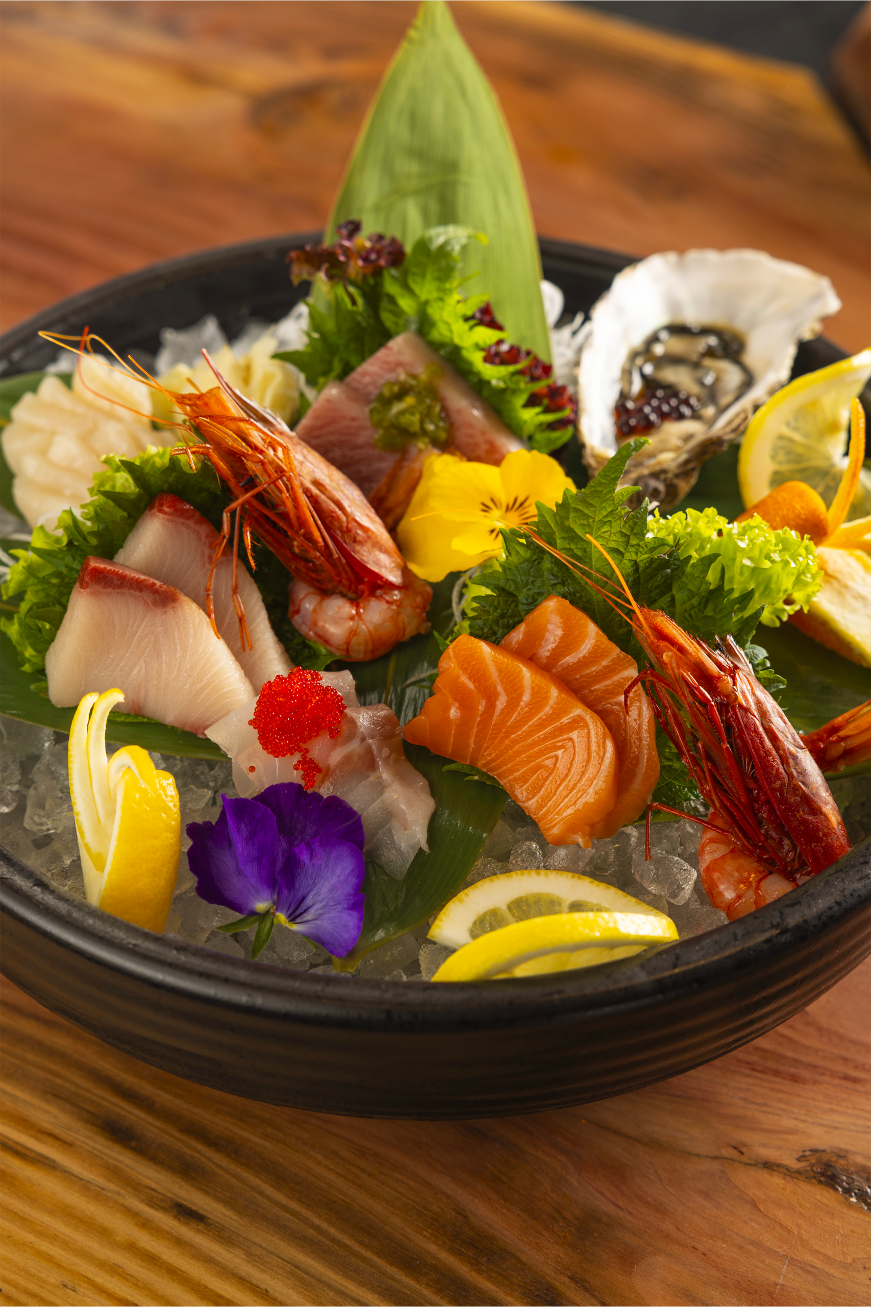 Maestoso piatto di sashimi servito su ghiaccio con colorate decorazioni floreali