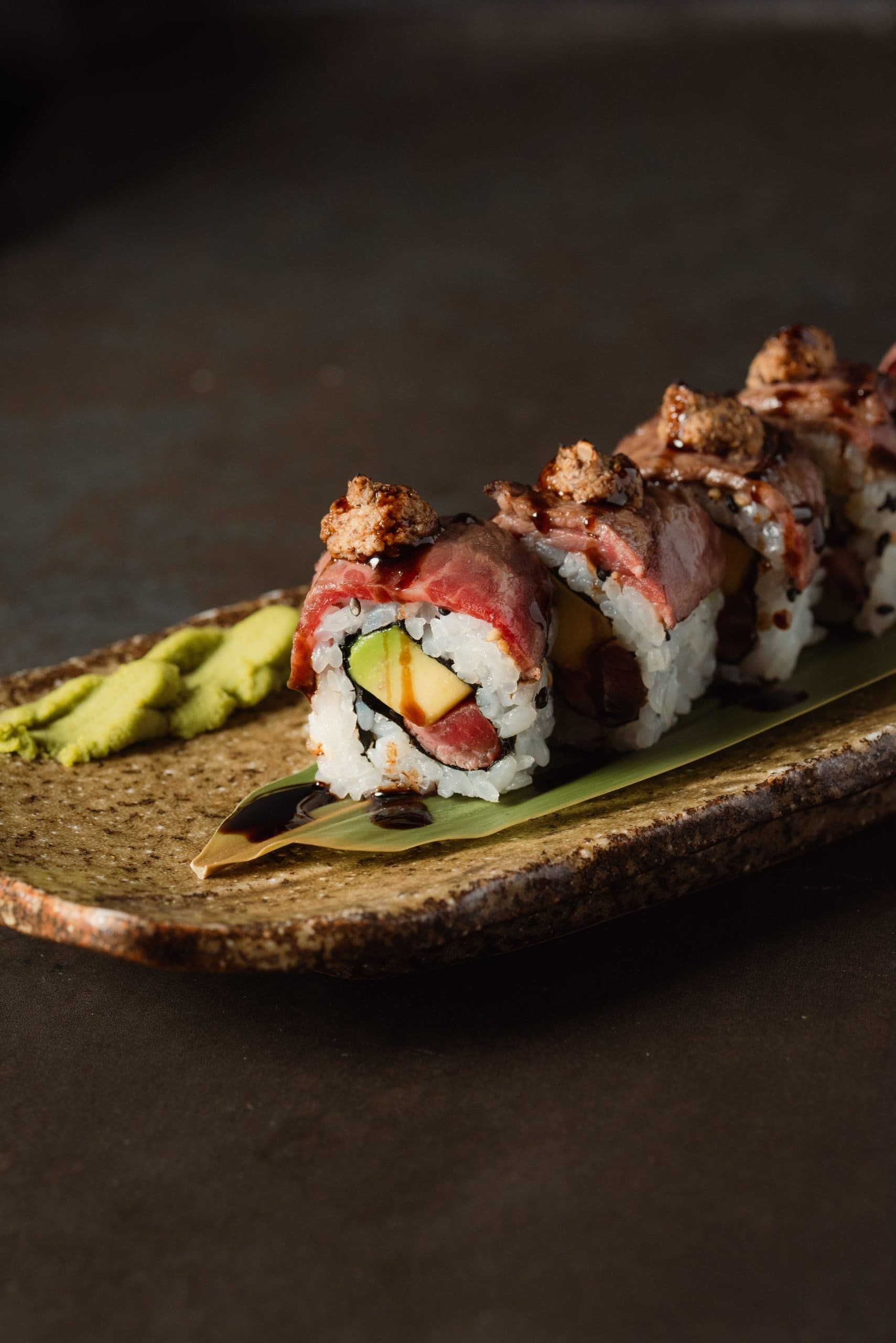 Sushi roll with meat, avocado and sauce on a plate
