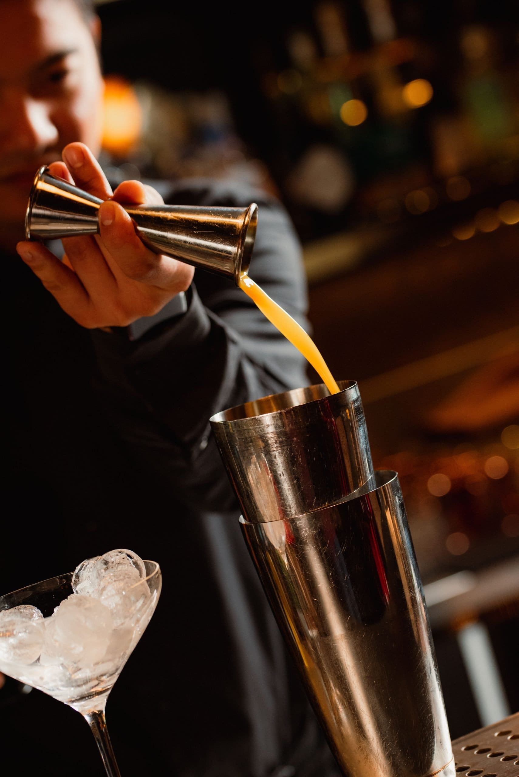 Bartender versa succo in uno shaker al bancone del bar