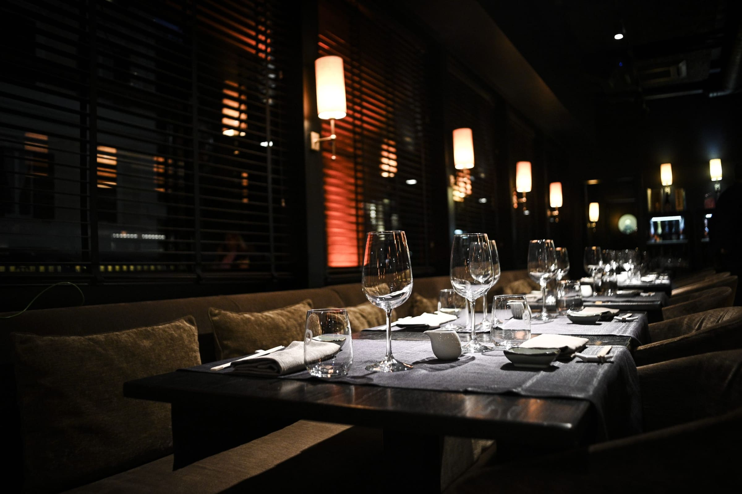 Interno di un ristorante elegante con tavoli apparecchiati e luci soffuse.