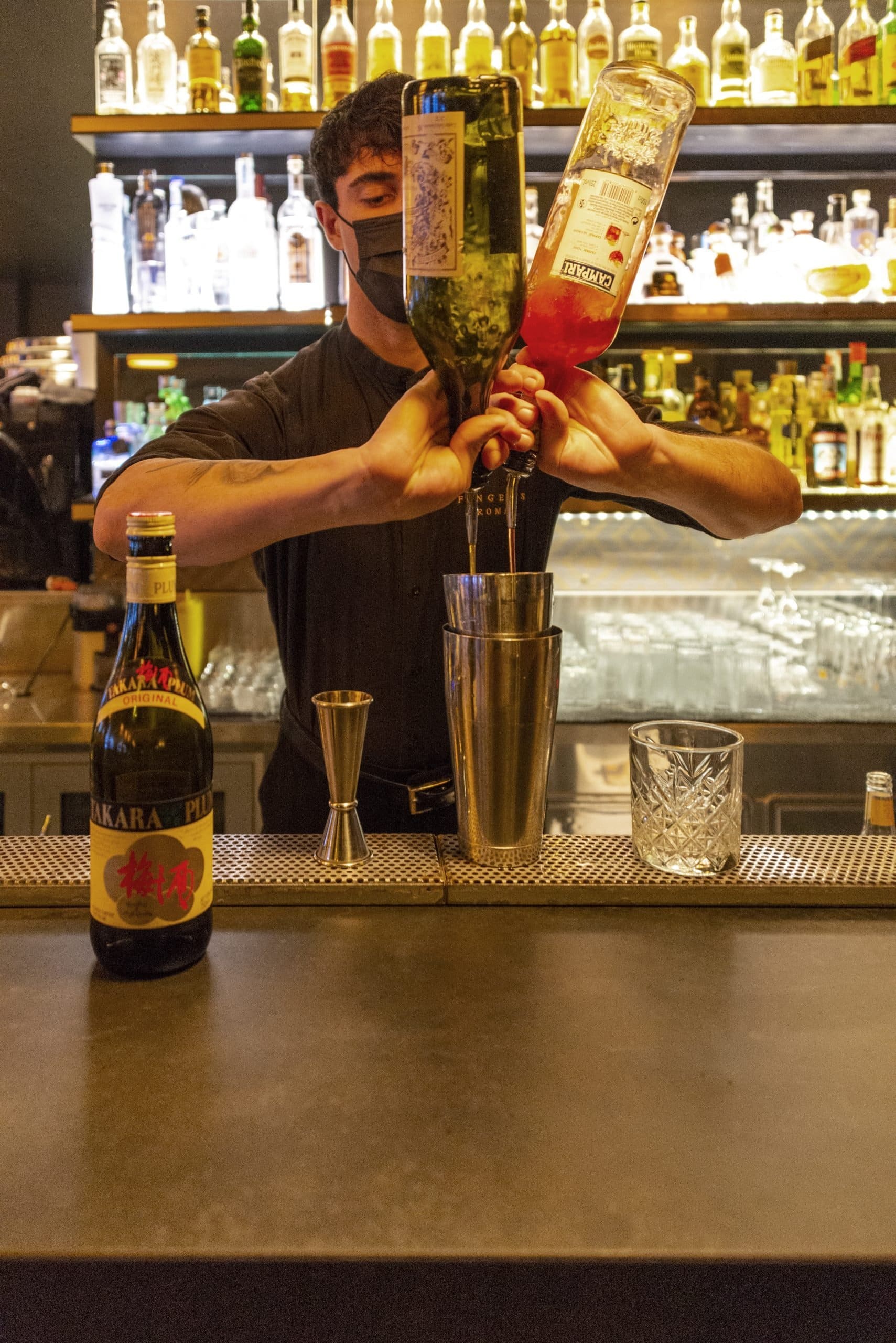 Bartender versa due bottiglie in uno shaker