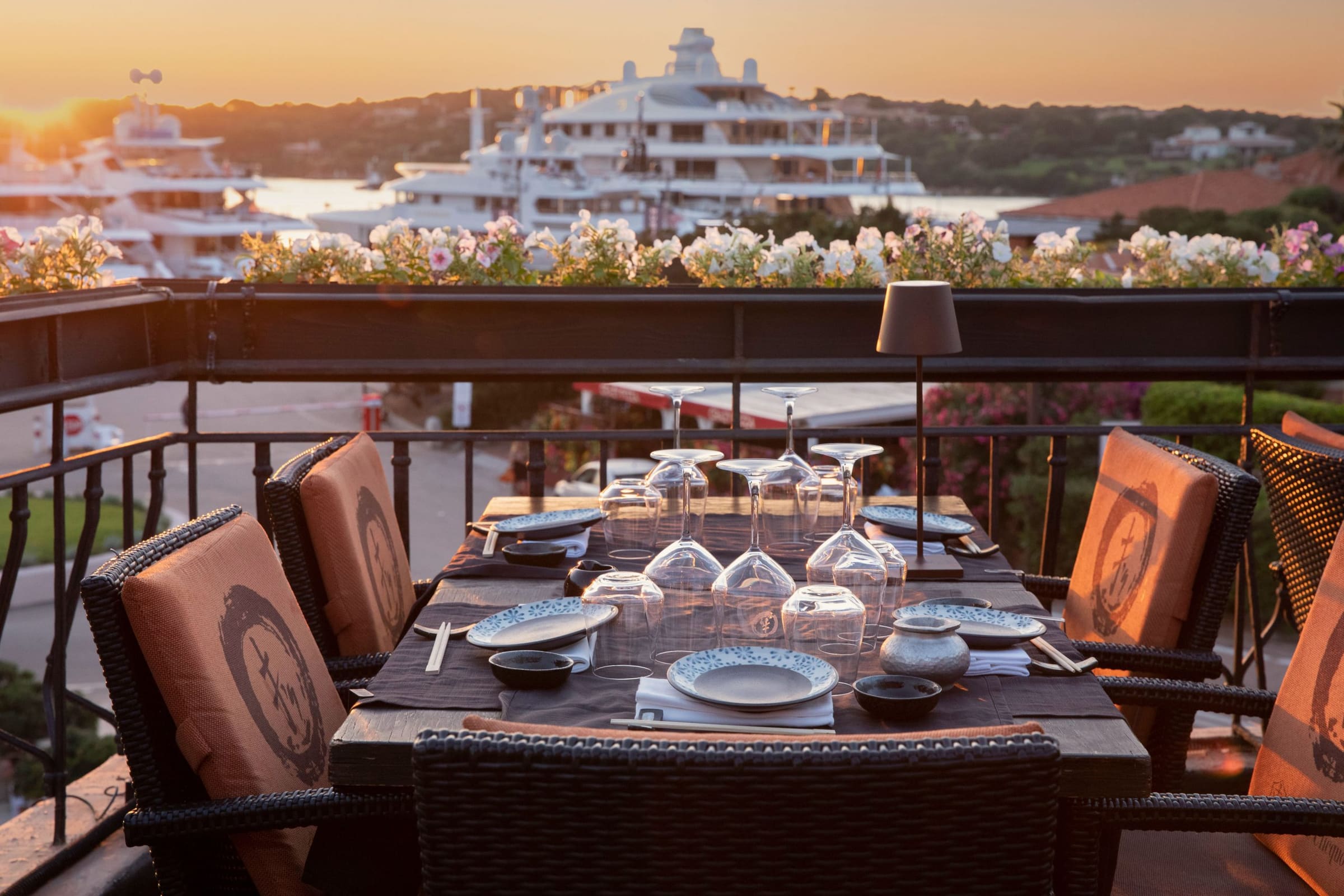 Table set on a terrace overlooking yachts at sunset