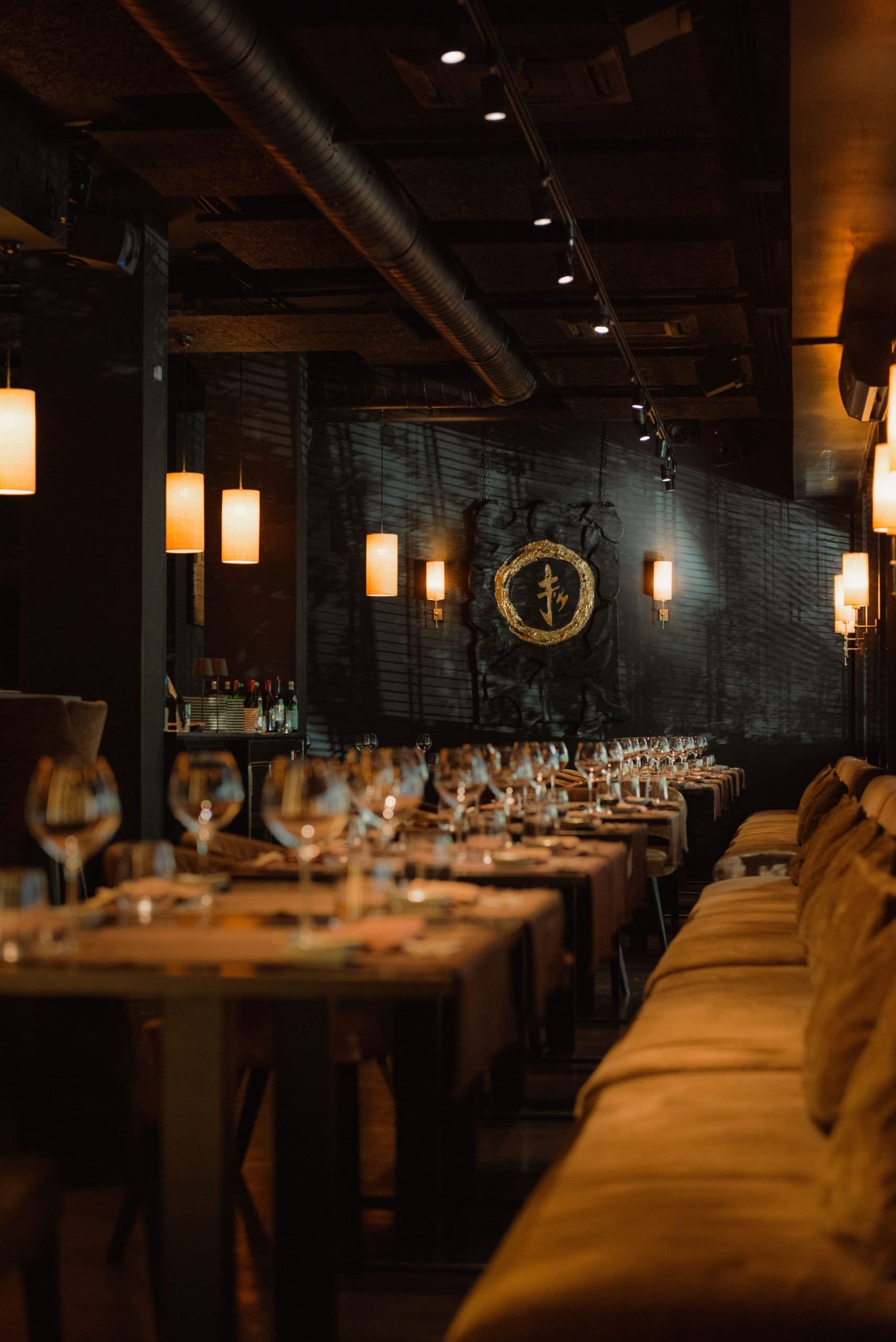 Interno di un ristorante elegante con tavoli apparecchiati e luci soffuse.