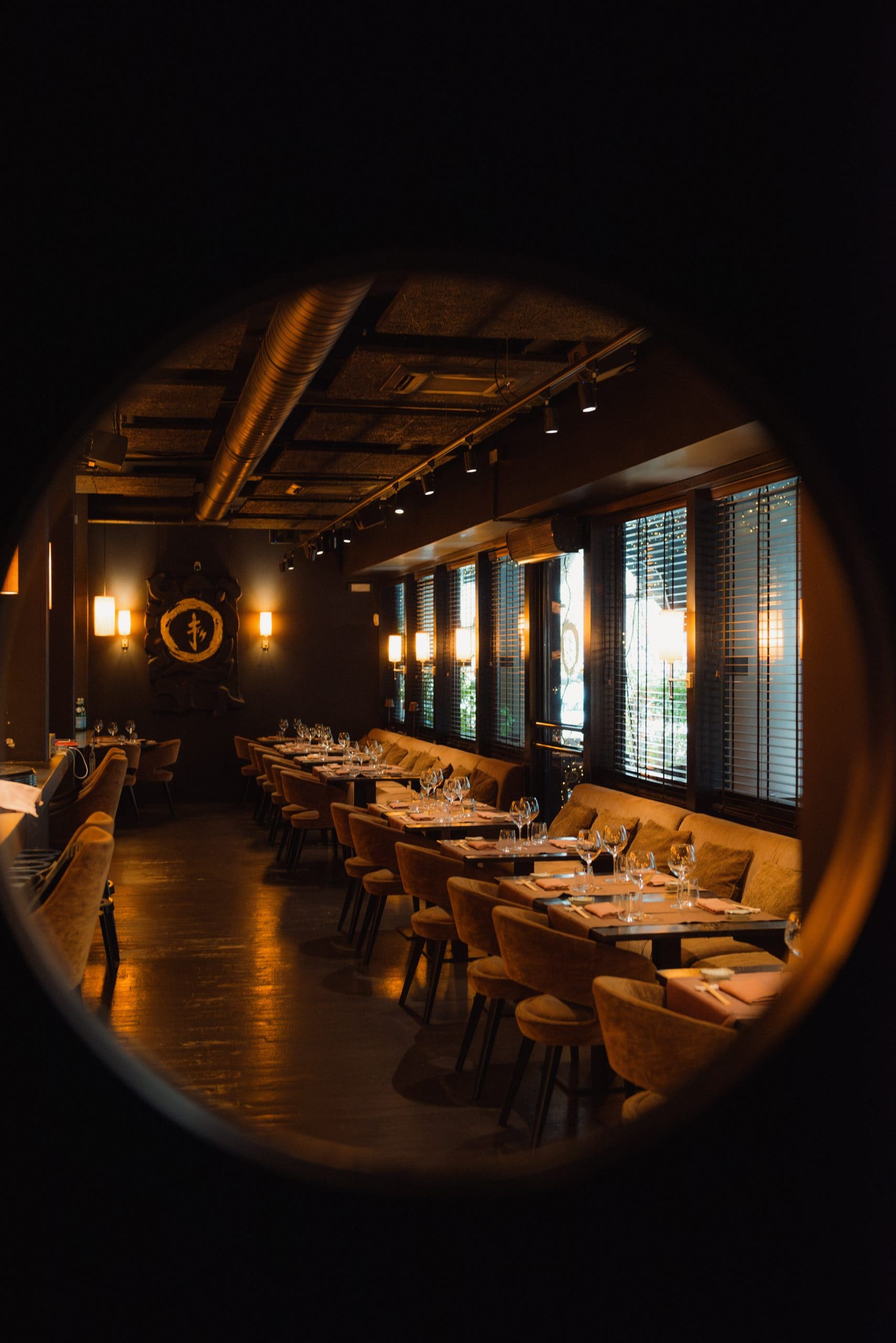 Interno di un ristorante con tavoli apparecchiati e illuminazione soffusa.